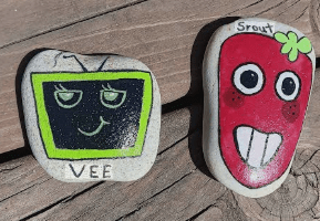 Hand-painted stones of Dandy's World characters Vee the TV and Sprout the strawberry.